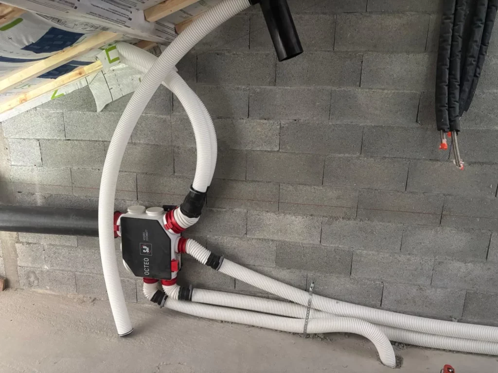 Bouche d'extraction VMC simple flux S&P hygroréglable installée sur un mur carrelé beige à Lullin.