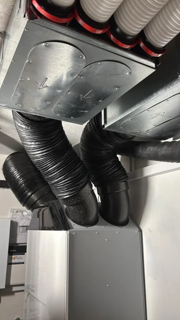 Unité centrale finalisant l'installation d'une VMC double-flux dans une maison neuve.