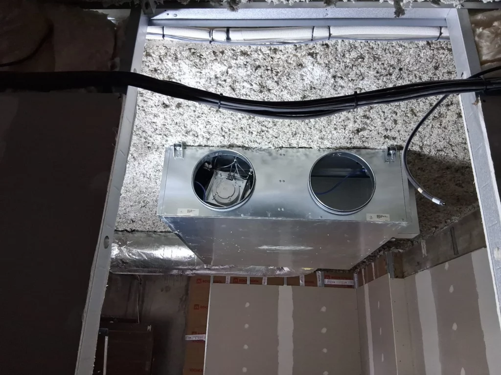 Caisson métallique de VMC double-flux fixé au plafond avant raccordement, crèche à Evian.