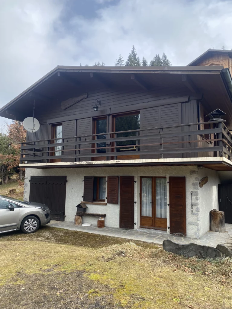 Façade d'un chalet de montagne rénové avec bardage bois sombre et isolation thermique par l'extérieur.