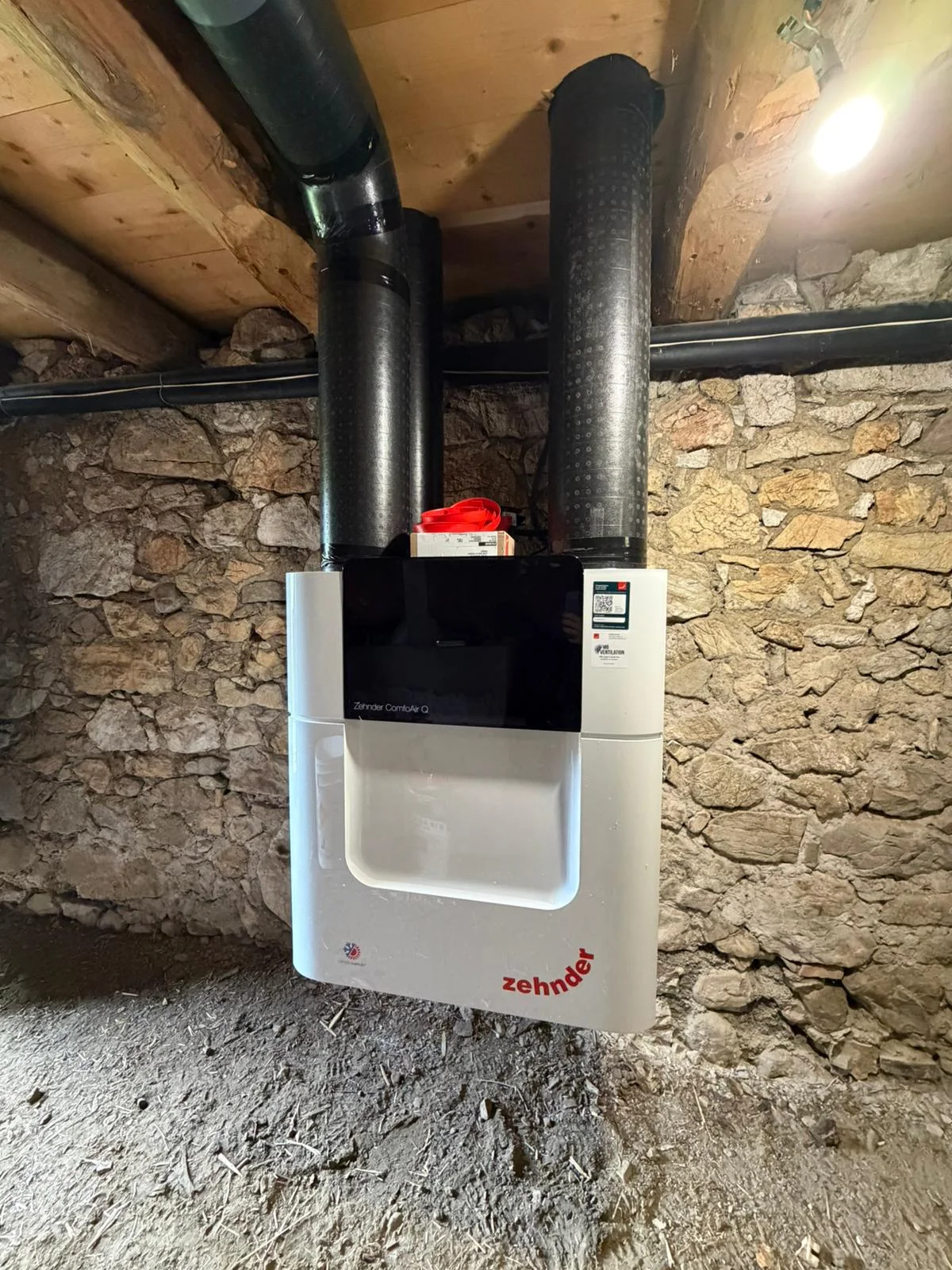 Centrale VMC double flux Zehnder ComfoAir Q installée en sous-sol contre un mur en pierre à Vacheresse