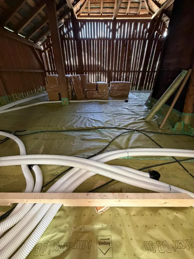 Pose des gaines de VMC double flux sur plancher isolant à Vacheresse, membrane frein-vapeur Ampatex visible